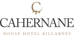 Het logo heeft een gestileerde gouden letter C met klimopbladeren eronder, boven het woord CAHERNANE in een groot zwart schreeflettertype - een elegante toets voor een jubileumcadeautje. Daaronder, in kleinere gouden schreefletters, staat HOUSE HOTEL KILLARNEY op een lichte achtergrond. | Echt Ierland Vakanties