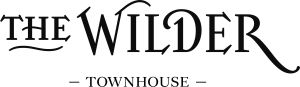 In zwarte tekst op een witte achtergrond staat THE WILDER in een decoratief, schreeflettertype met elegante versieringen. Daaronder staat TOWNHOUSE in hoofdletters, met aan weerszijden een lijn. Het algemene ontwerp is verfijnd en stijlvol. | Echt Ierland Vakanties