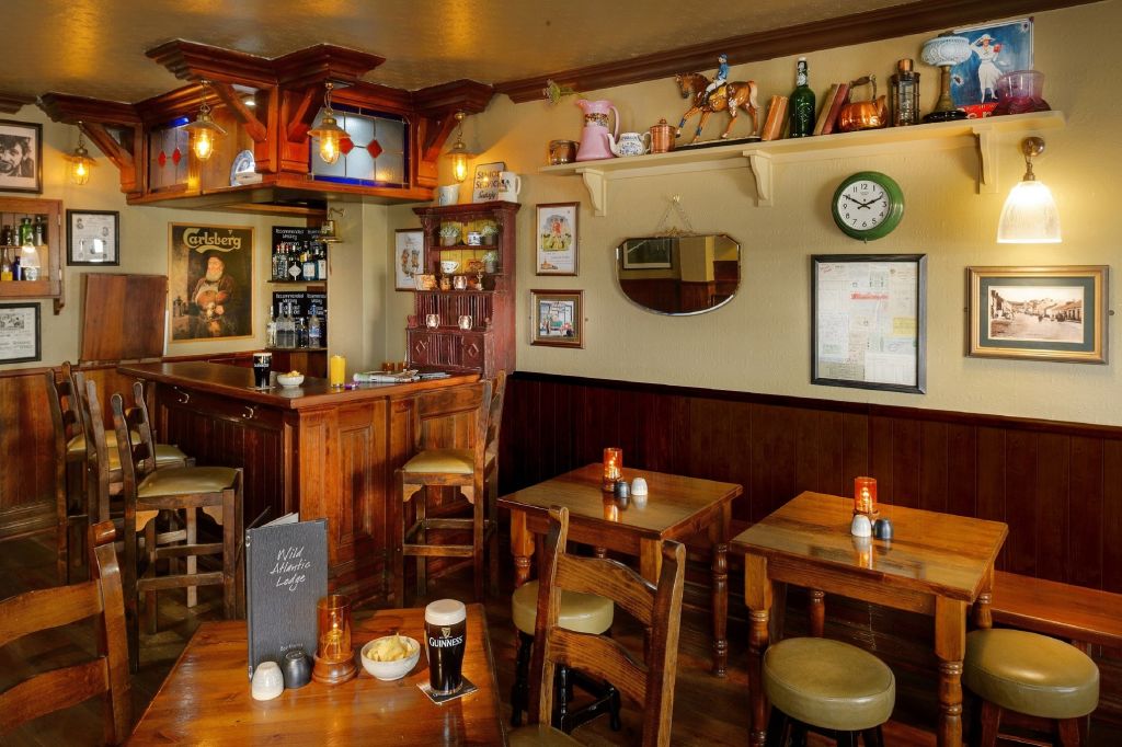 Een gezellig pubinterieur met ouderwetse charme, met houten tafels en stoelen, een klein bargedeelte en vintage decoraties. Warmgele verlichting accentueert drankjes, snacks en ingelijste foto's op de crèmekleurige muren - op steenworp afstand van een boetiekhotel in het centrum van Kilkenny. | Echt Ierland Vakanties